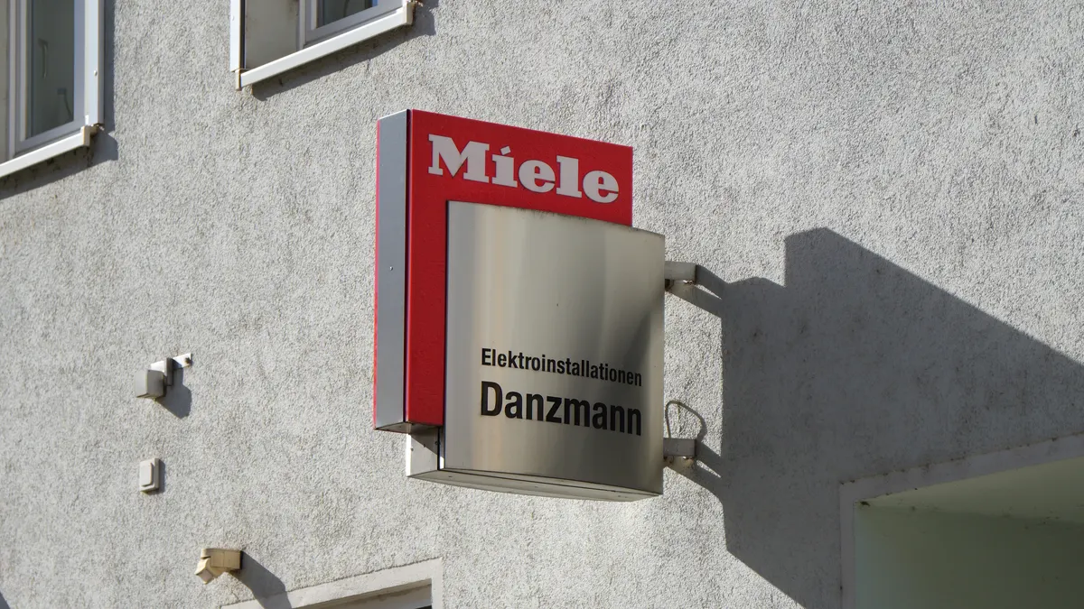 Schild von Elektromeister Danzmann mit Miele-Schild an der Fassade des Ladengeschäfts