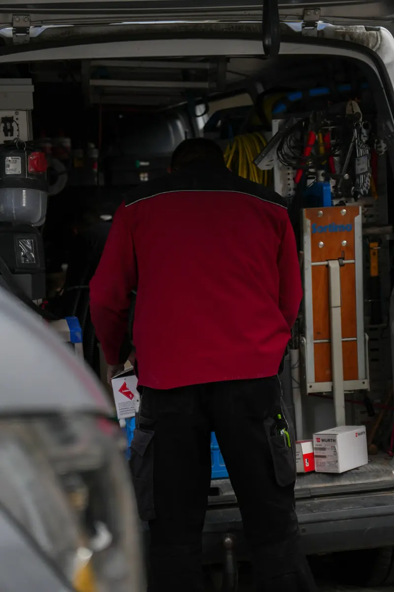 Monteur holt Material aus dem Laderaum des Transporters